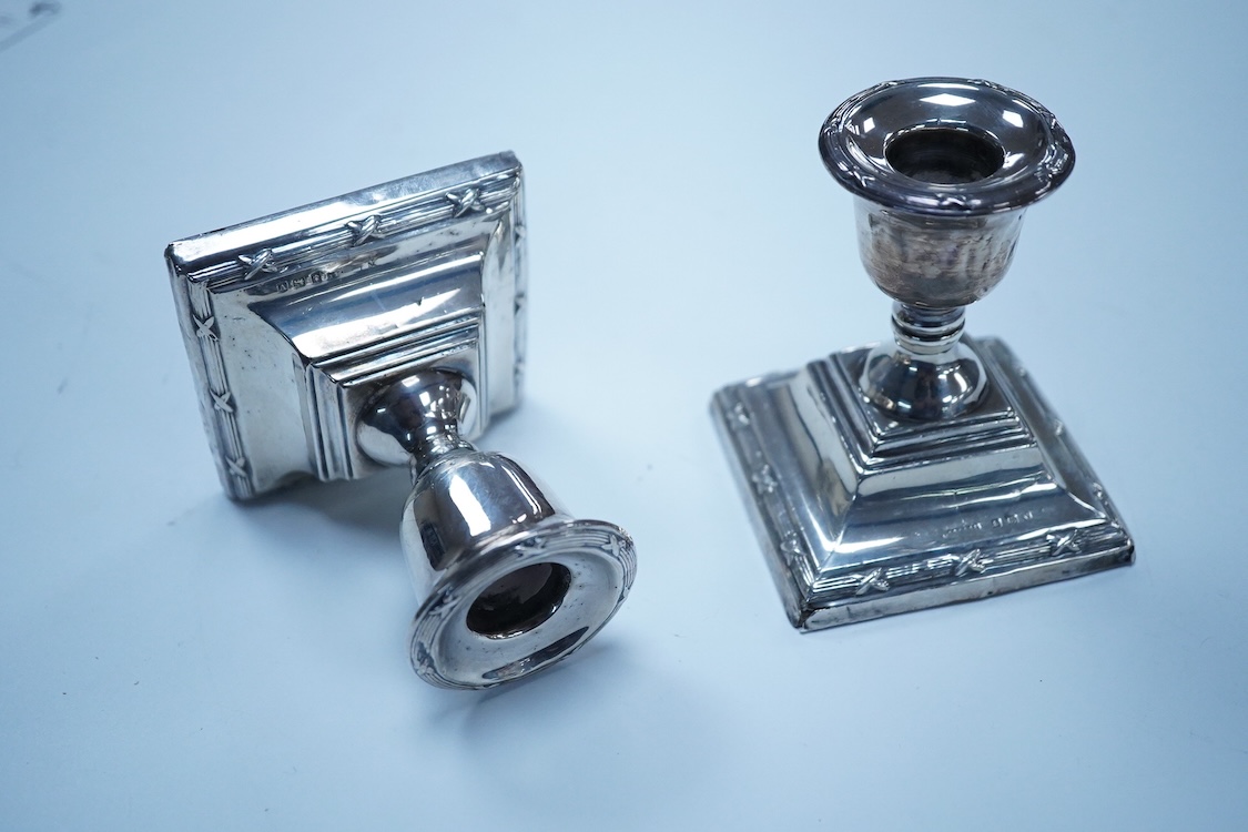 A pair of George V silver mounted dwarf candlesticks, Birmingham, 1920, height 86mm (a.f.), together with a cased Victorian silver beaded Old English pattern christening knife and fork, George Adams, London, 1881.